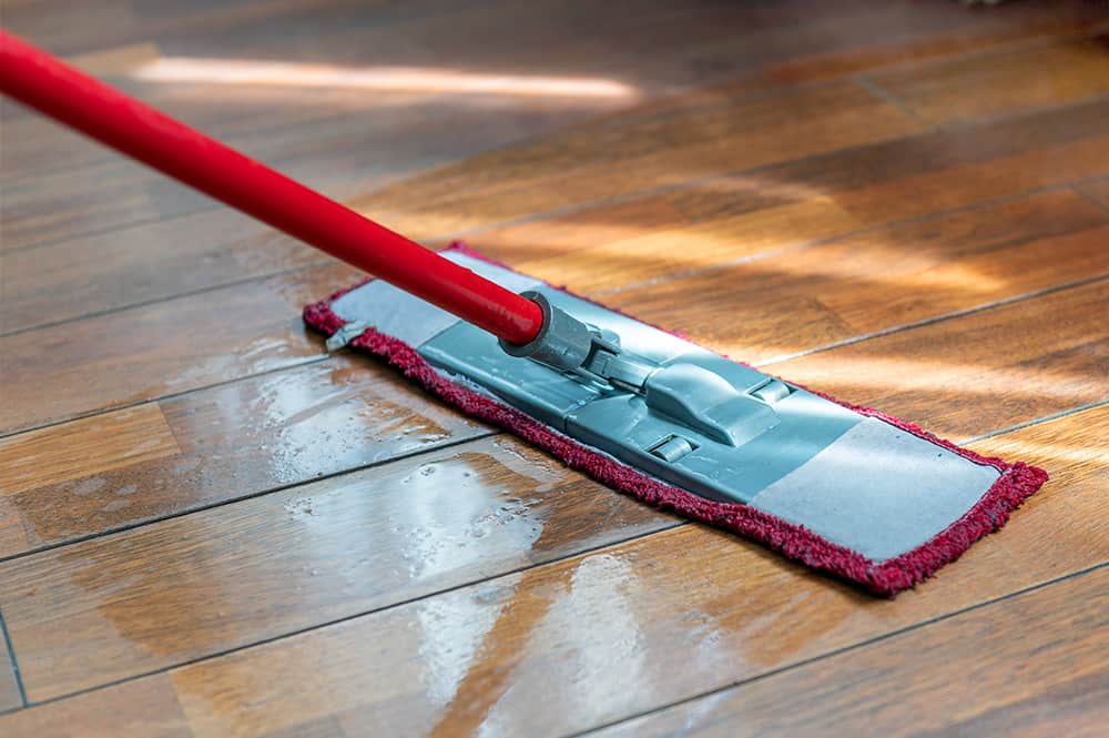 Clean Oil Finished Wood Floors | A mop washing a wooden floor in an apartment. Concept of care for the cleanliness of the apartment. Mopping the floor