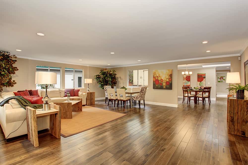 Wood Floor Care | Large living room with tan rug and white leather sofas.