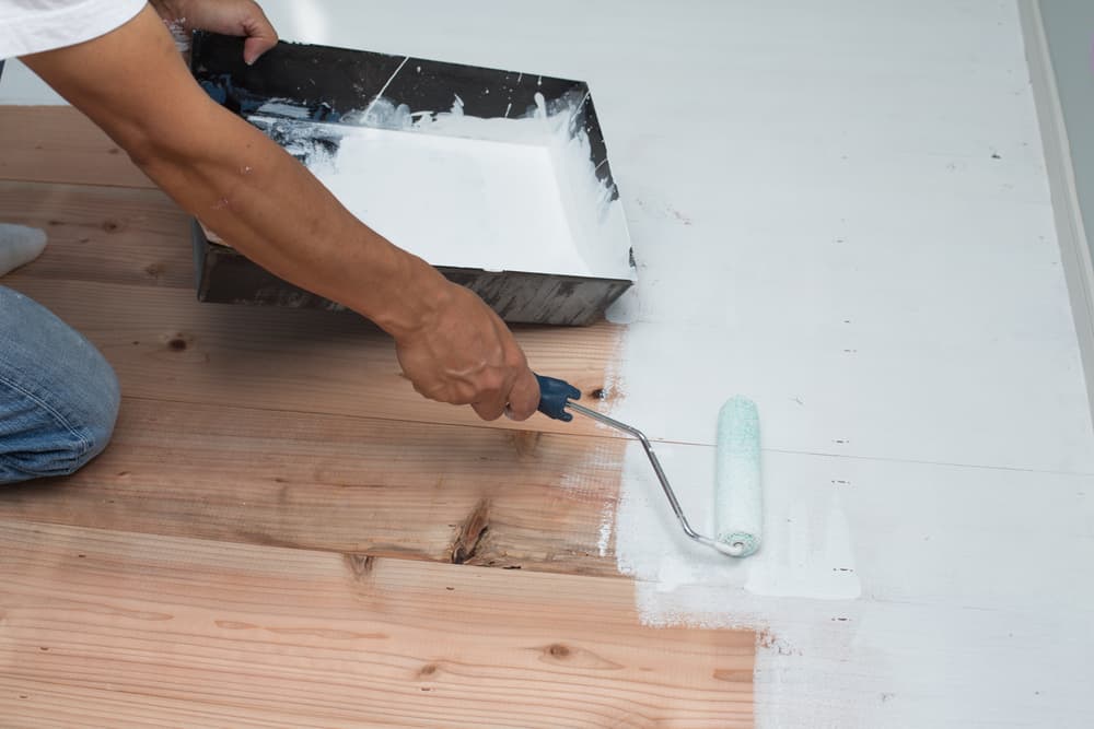 paint wood floors | someone painting a wooden floor
