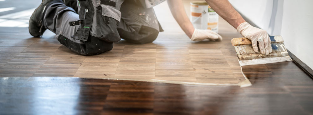 Best Ways To Refinish Wood Floors | man oiling wood floor on hands and knees