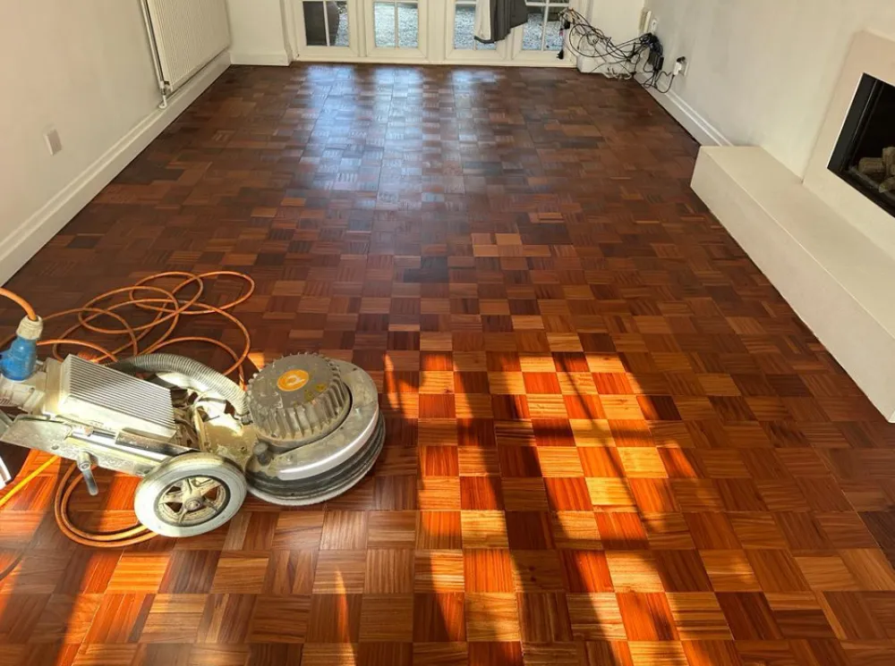 Wooden floor restoration west sussex | Parquet flooring in a house with someone using a rotary sander.