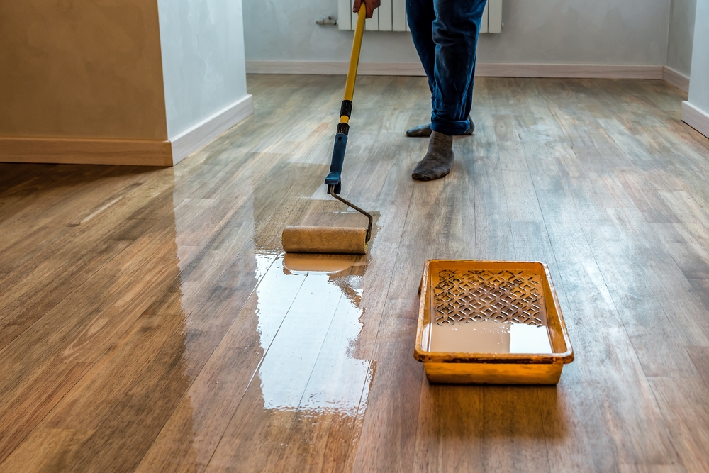 Man finishing floor with a varnish